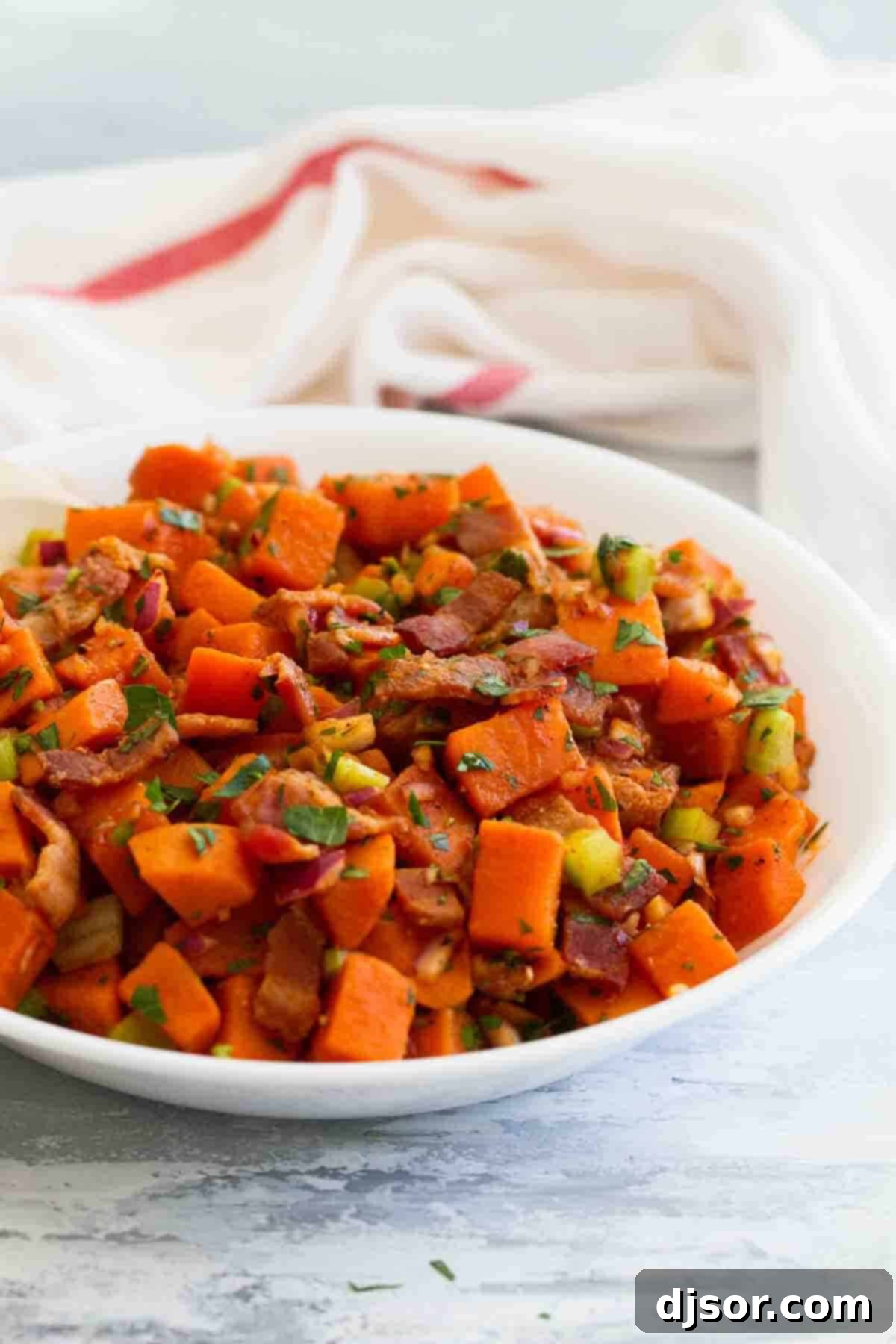 Freshly Prepared Sweet Potato Salad Close-up of sweet potato salad with bacon and fresh herbs in a white bowl, ready for serving.