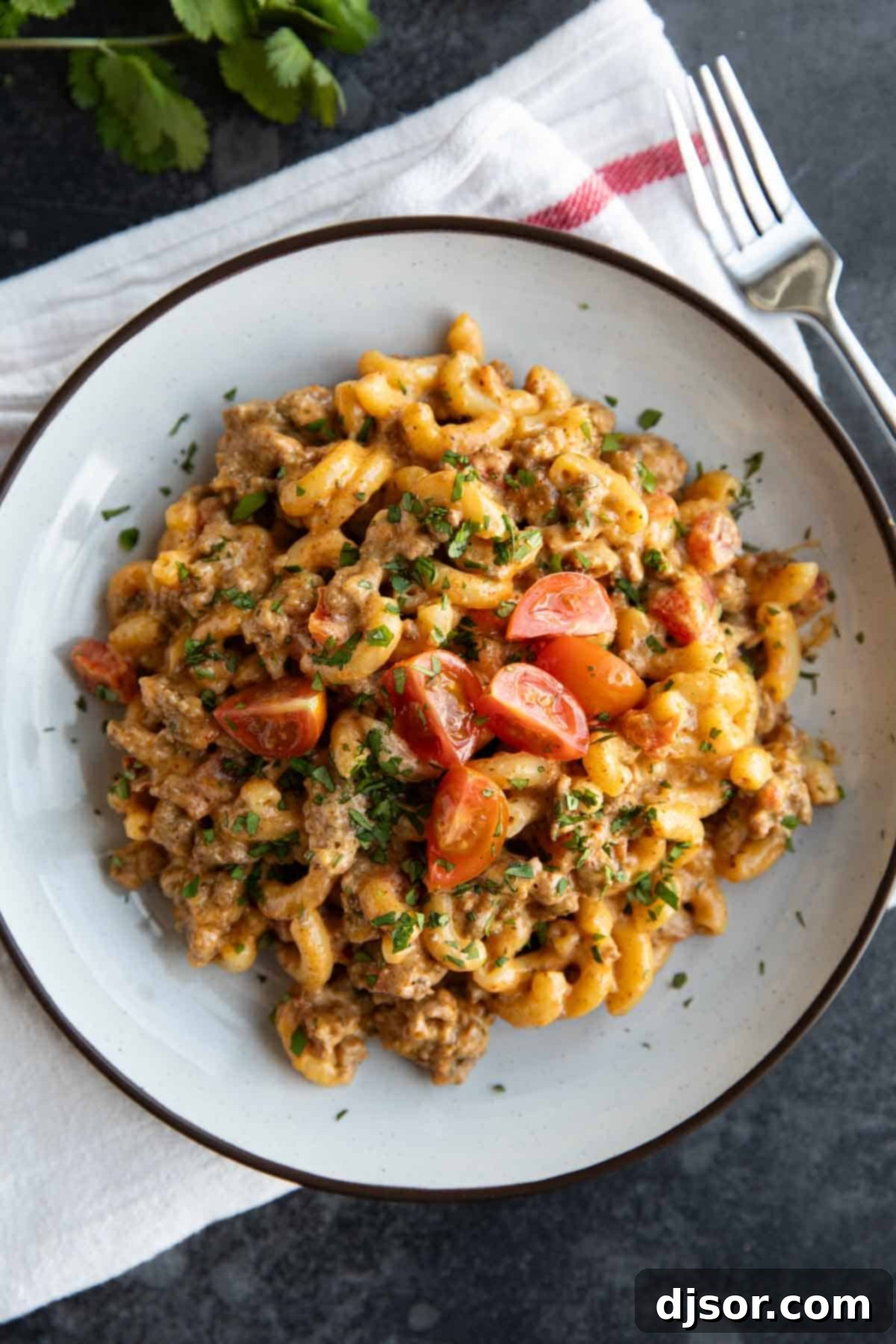 Close-up shot of Taco Mac and Cheese in a bowl, showing creamy texture, ground beef, and diced tomatoes.