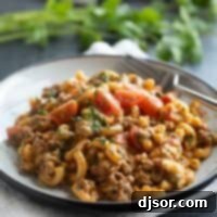 Plate filled with taco Mac and cheese topped with tomatoes and cilantro.