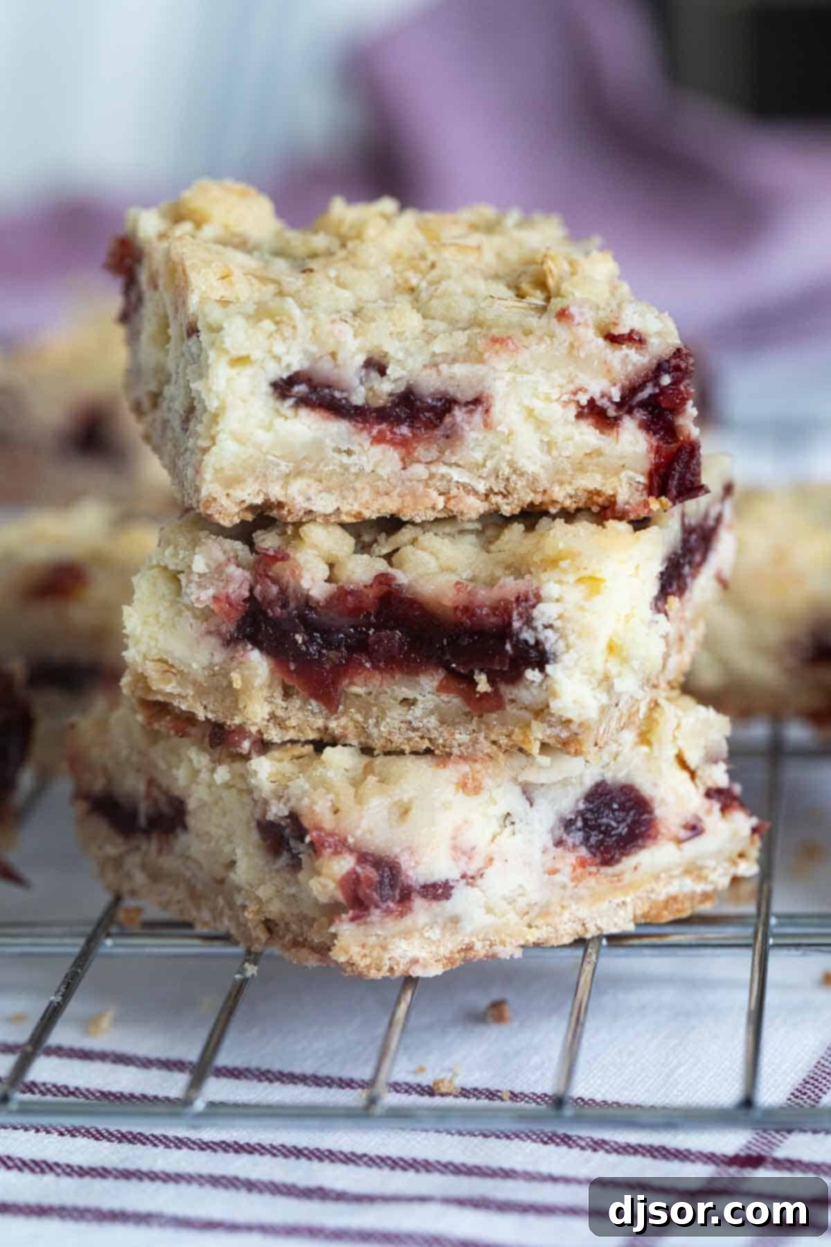 Three Cranberry Cheesecake Bars stacked on top of each other.