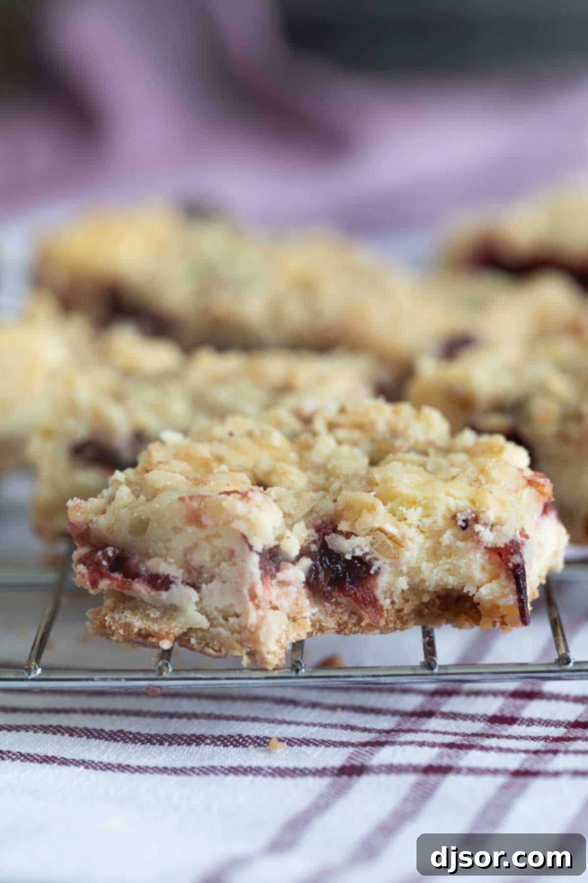 Cranberry Cheesecake Bar on a cooling rack with a bite taken from it.