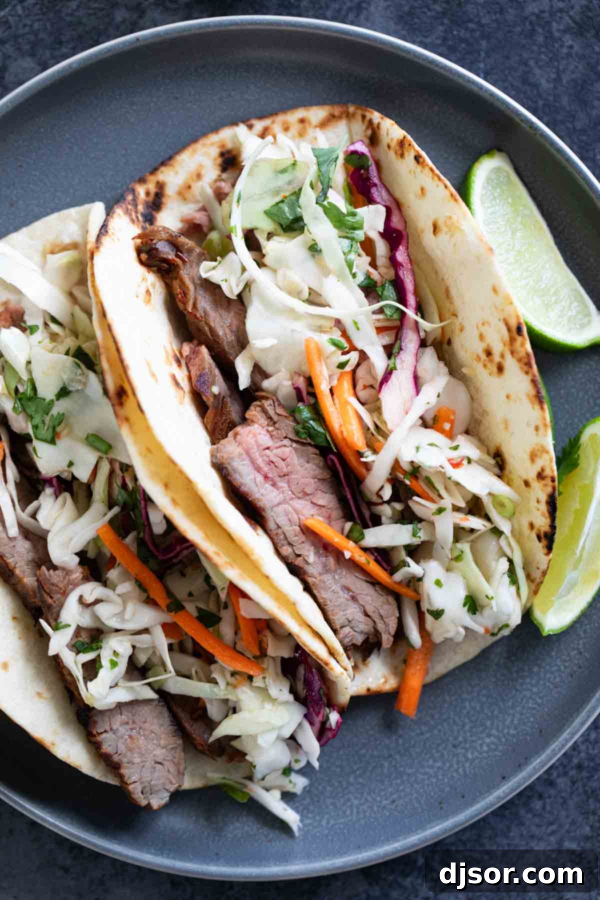 Siam Street Tacos 8 Two vibrant Thai Tacos served on a white plate, garnished with fresh cilantro and lime wedges.