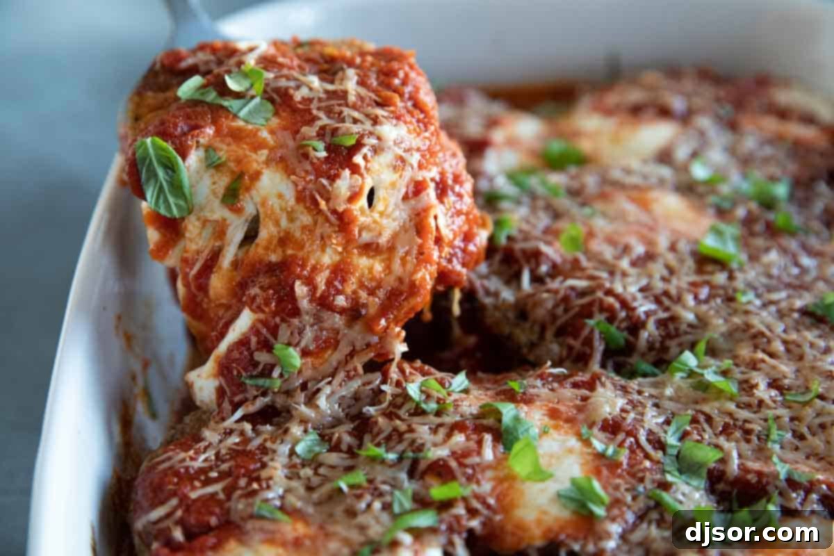Breaded slices of eggplant, lots of cheese, and marinara sauce make up this Eggplant Parmesan that the whole family will love. eggplant parmesan being taken out of a casserole dish with a scoop.