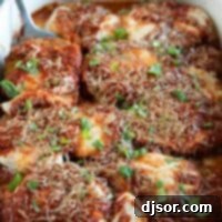 Classic Eggplant Parmesan 2 white casserole dish with eggplant parmesan with spatula.