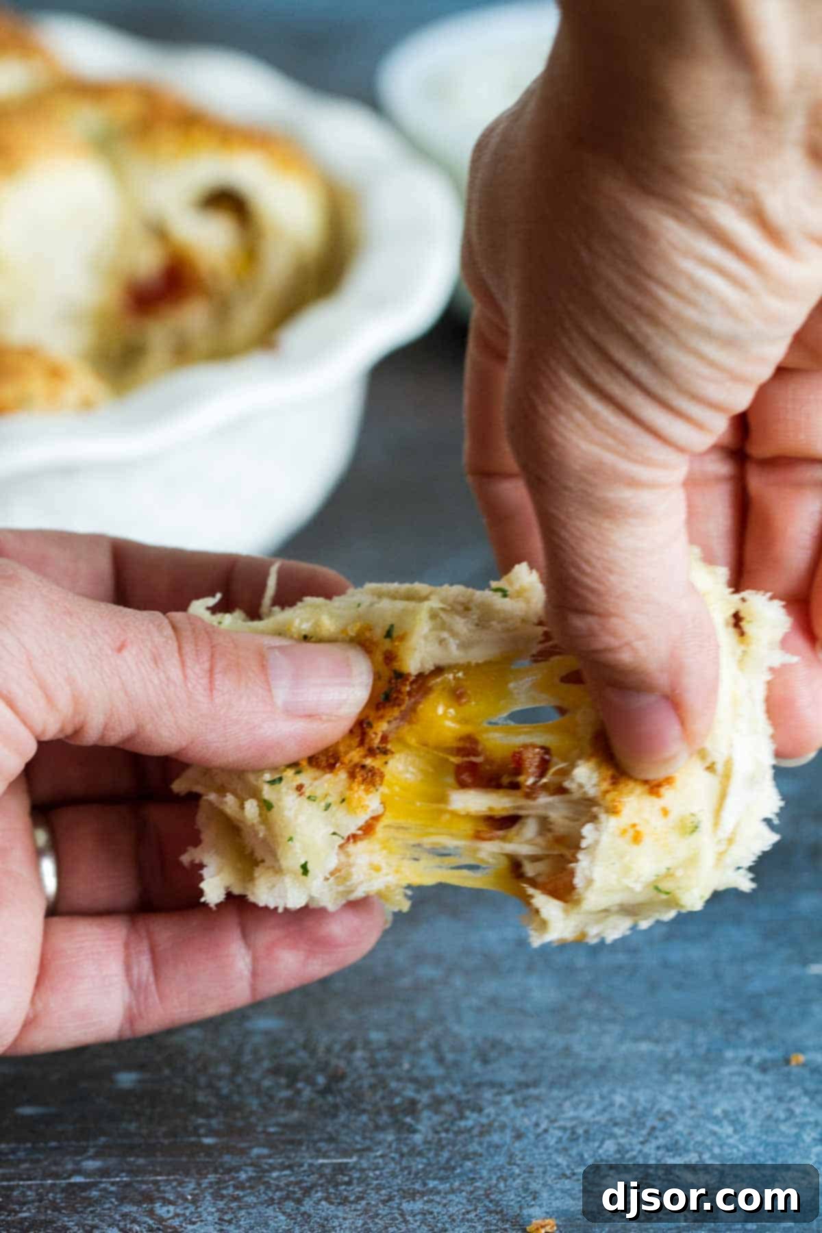 A Stuffed Pizza Roll being pulled apart, showcasing the melted cheese pull and the chicken bacon ranch filling inside.