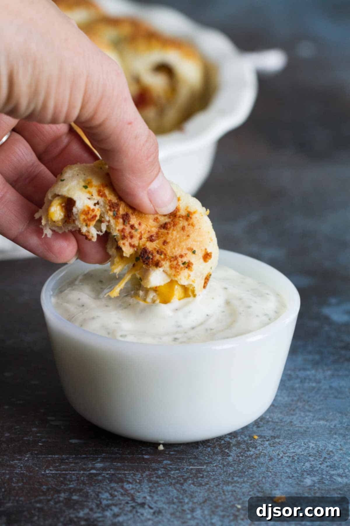 A hand dipping a golden-brown Stuffed Pizza Roll into a small bowl of creamy ranch dressing, highlighting the perfect bite.