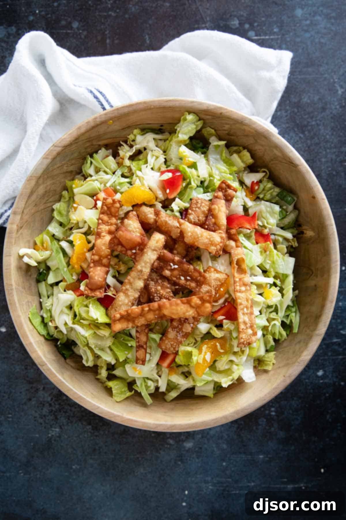 Wooden bowl filled with Asian Chopped Salad topped with fried wonton strips.