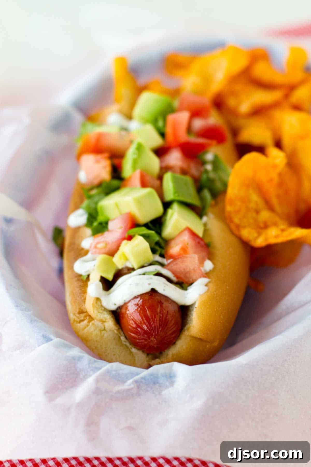 Hot dog topped with bacon, lettuce, avocado, and tomato.