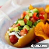 Bacon, lettuce, avocado, and tomato topped hot dog in a parchment paper lined basket.