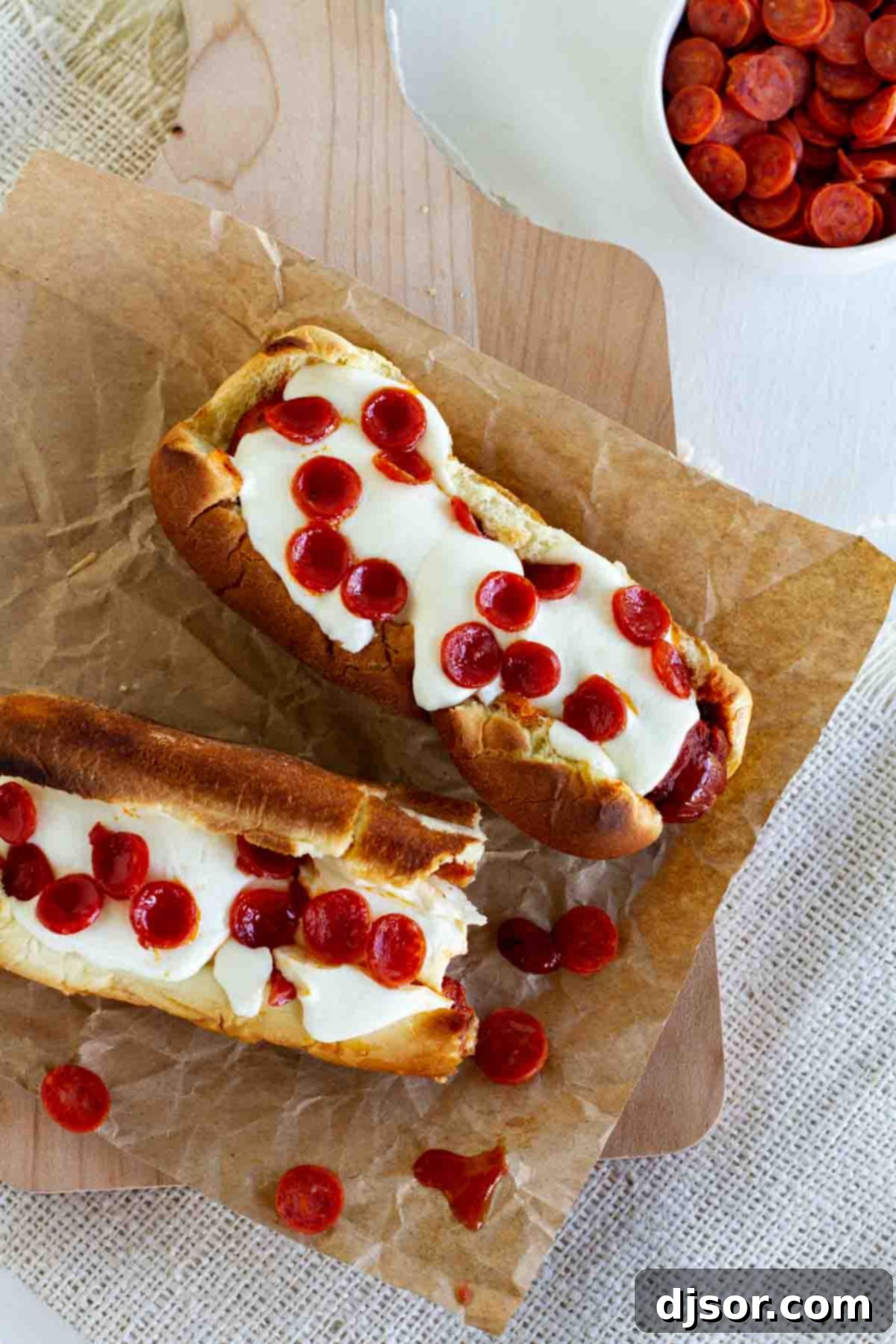 Quick and Easy Pizza Hot Dogs with Pepperoni Two gourmet pizza hot dogs topped with mini pepperoni on a serving board.