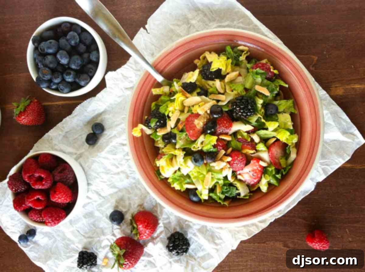 This Summer Chopped Salad is a feast for the eyes and the palate, highlighting the best of seasonal produce. Overhead view of a beautifully arranged Summer Chopped Salad featuring an assortment of colorful berries, fresh greens, and glistening sugared almonds.