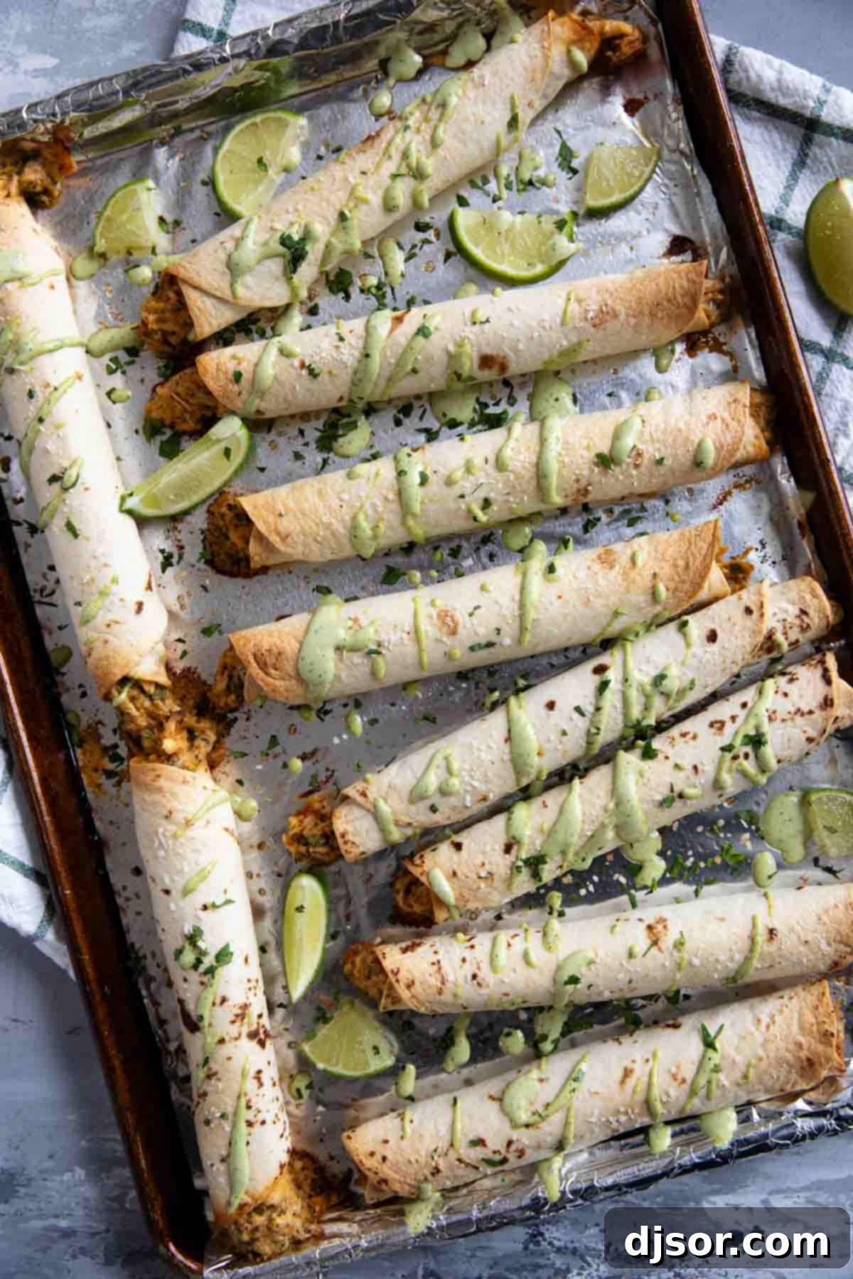 Crispy Chicken Flautas 7 Chicken Flautas drizzled with cilantro ranch on a baking sheet.
