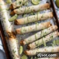 Crispy Chicken Flautas 10 Chicken Flautas drizzled with cilantro ranch on a baking sheet.