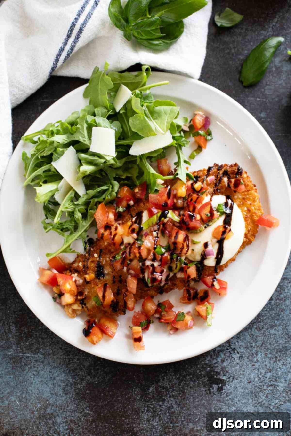 Perfectly cooked Bruschetta Chicken on a white plate, drizzled with a rich balsamic glaze and garnished with fresh basil leaves, ready to be enjoyed.