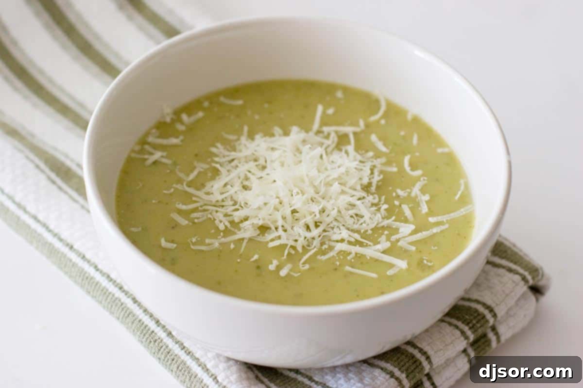 white bowl with zucchini soup with shredded parmesan cheese on top