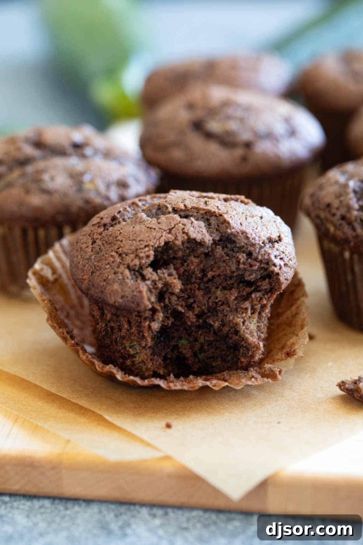 Chocolate zucchini muffin unwrapped with a bite taken from it.