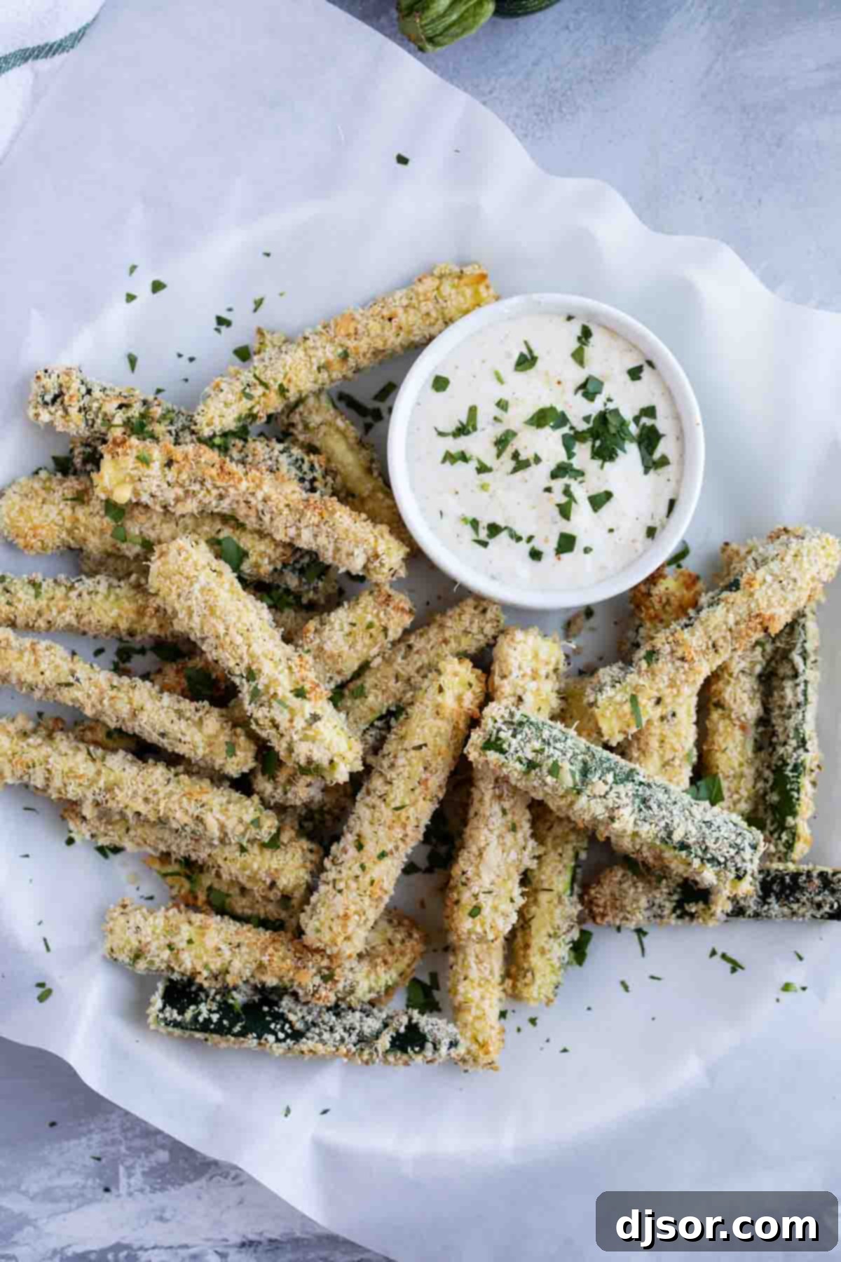 baked zucchini fries stacked on parchment paper