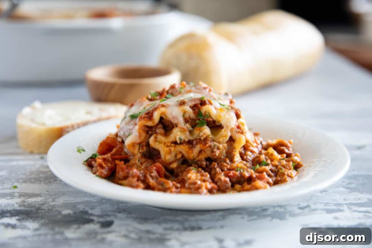 Easy Lasagna Pinwheels 2 A plate featuring perfectly golden-brown Lasagna Roll Ups, topped with a rich meat sauce and melted cheese, with a side of crusty bread in the background.