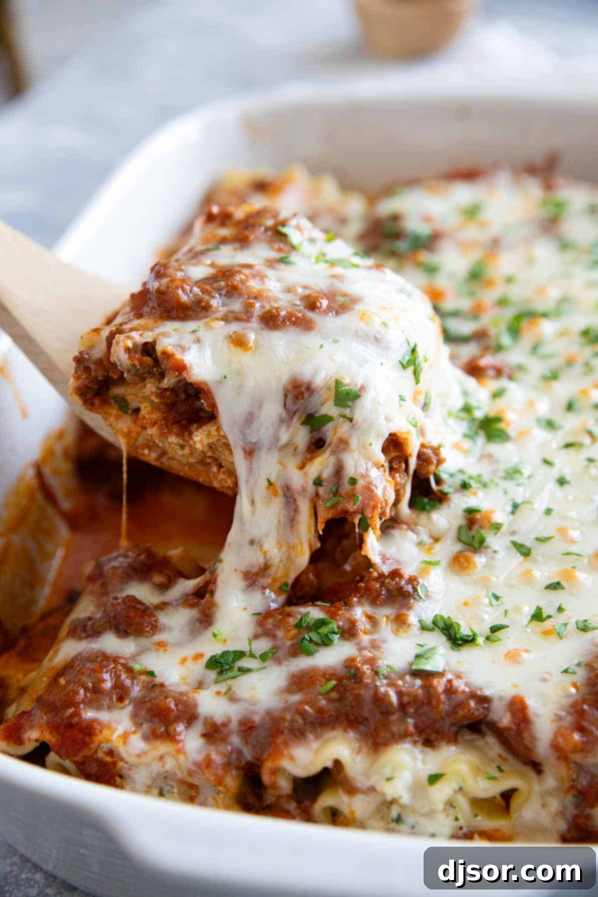 Easy Lasagna Pinwheels 9 A single Lasagna Roll Up being carefully lifted from a baking dish with a spatula, showcasing its melted, stretchy cheese and spiraled layers.