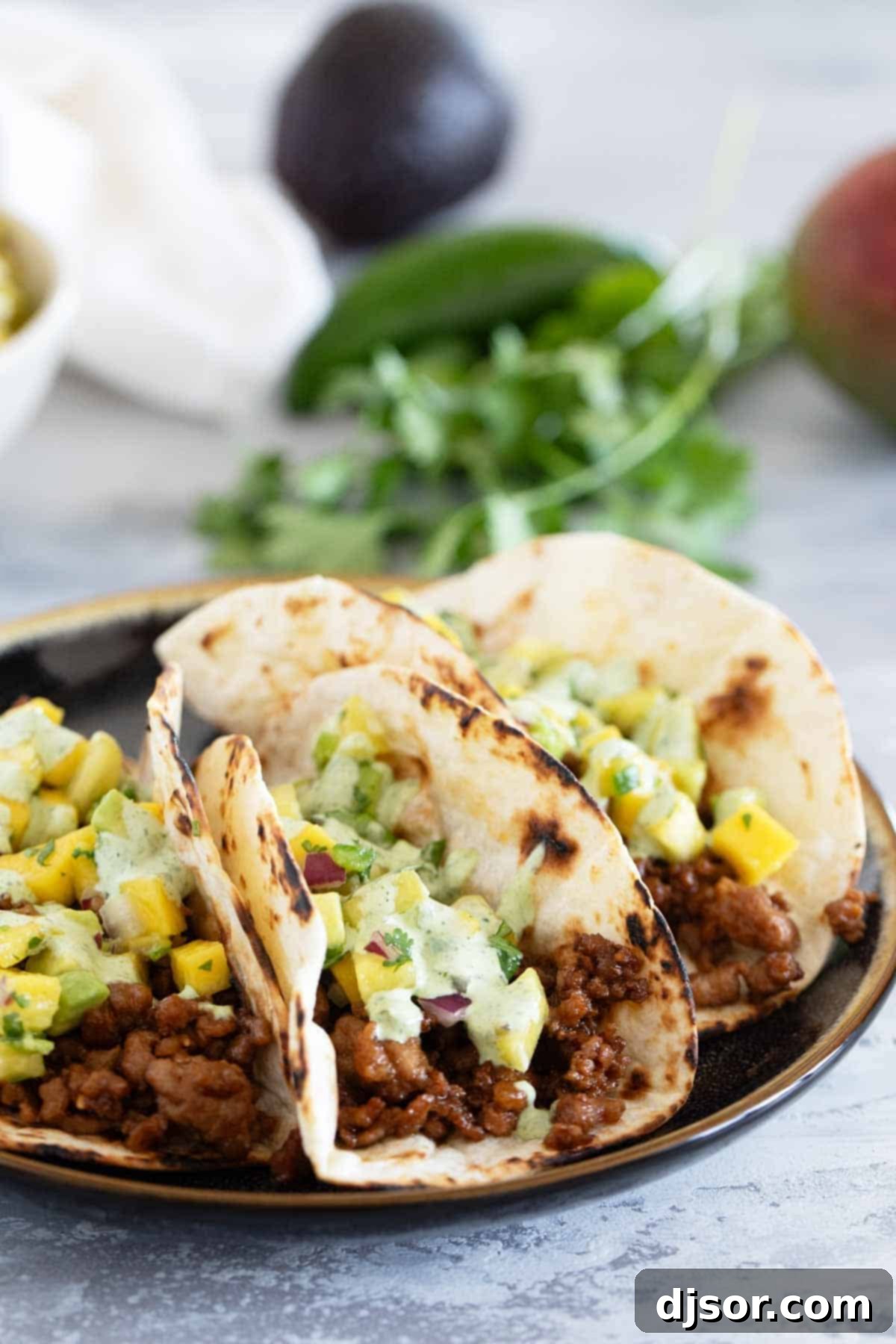 Island Taco Fiesta 8 Hawaiian Tacos served on a white plate, garnished with fresh fruit salsa and a generous drizzle of cilantro lime sauce.