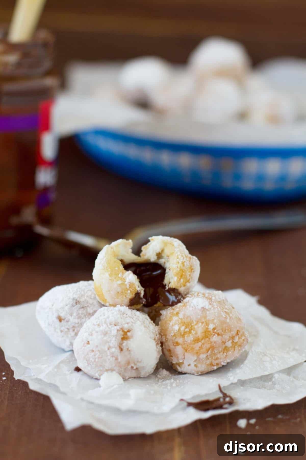 Chocolate Hazelnut Stuffed Donut Holes stacked on top of each other with one broken open to reveal the delicious filling.