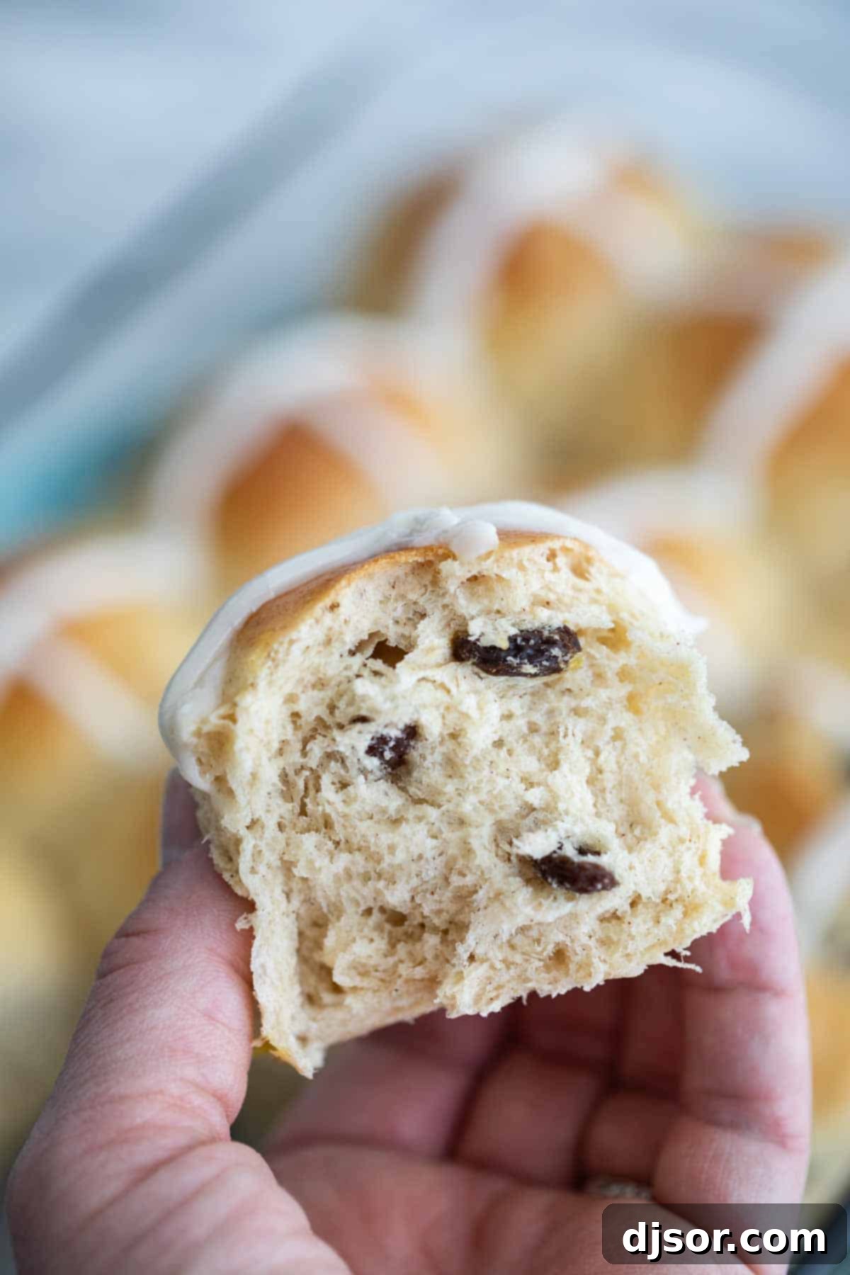 Fluffy Hot Cross Bun with Raisins Close-up of a Hot Cross Bun sliced open to reveal its fluffy texture and plump raisins inside.