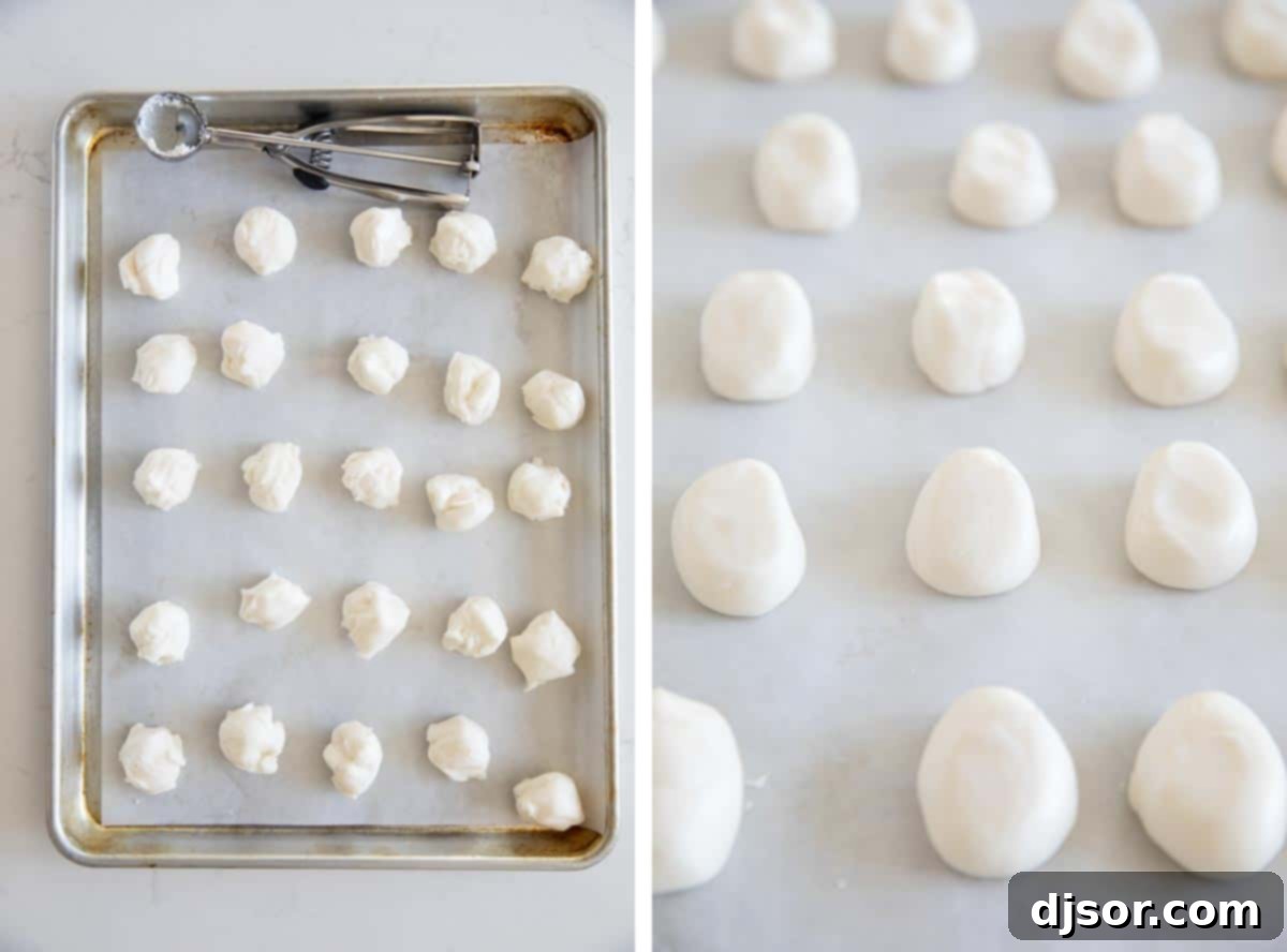 Shaping the Marshmallow Egg Centers A baking sheet lined with parchment paper, holding several small, perfectly formed egg-shaped marshmallow truffle centers, freshly removed from the refrigerator and ready for the next stage of preparation.