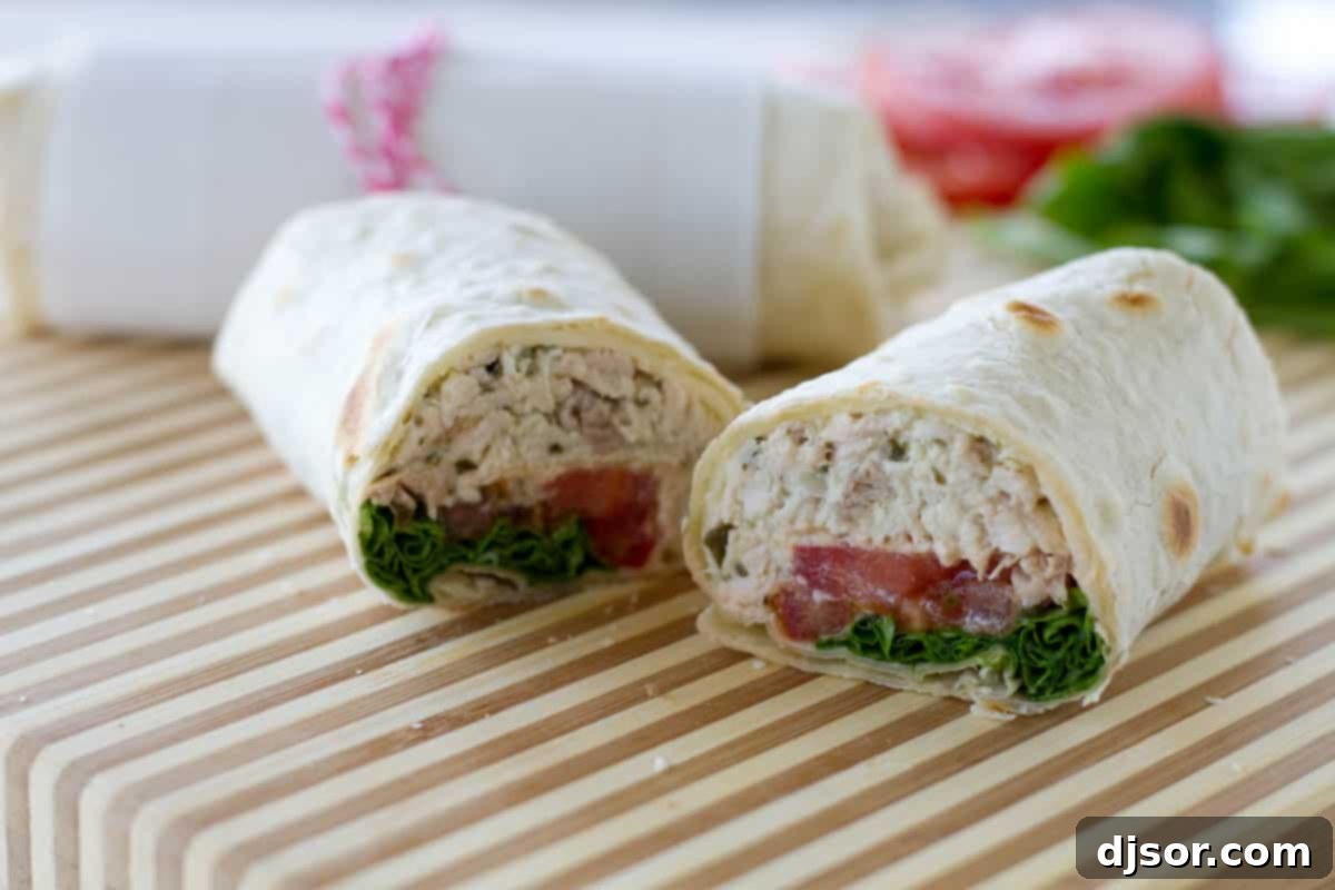 Half of a chicken pesto wrap, showcasing the delicious interior with chicken, pesto, cheese, tomato, and lettuce.