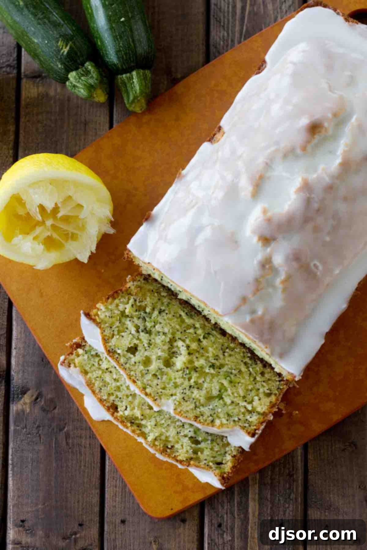 An overhead shot showcasing the beautiful golden-brown crust of a Glazed Lemon Poppy Seed Zucchini Bread loaf, generously drizzled with a sweet lemon glaze.