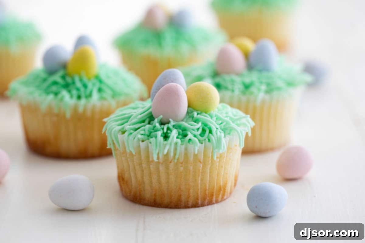 Lemon Cupcakes with Easter Decorations on top. The light lemon cupcake is topped with green grass frosting and small candy Easter eggs, embodying the freshness of spring.