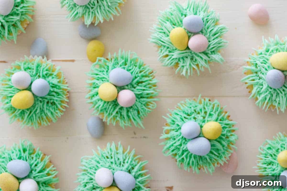 Easter cupcakes topped with green grass buttercream and Easter egg candy on top, showcasing the vibrant spring theme.