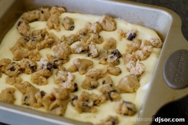 Placing pieces of cookie dough on top of the cheesecake layer for caramel cookie cheesecake bars.