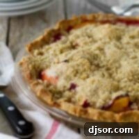 Raspberry Ripple Peach Pie 2 A full Peach Melba Pie, beautifully baked with a golden crumble topping, ready to be served.