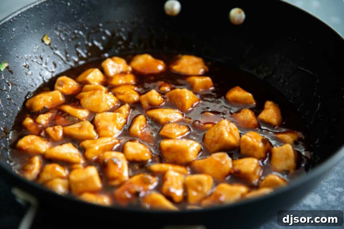 A skillet filled with golden-brown chicken pieces generously coated in a rich, glossy General Tso sauce, simmering to perfection.