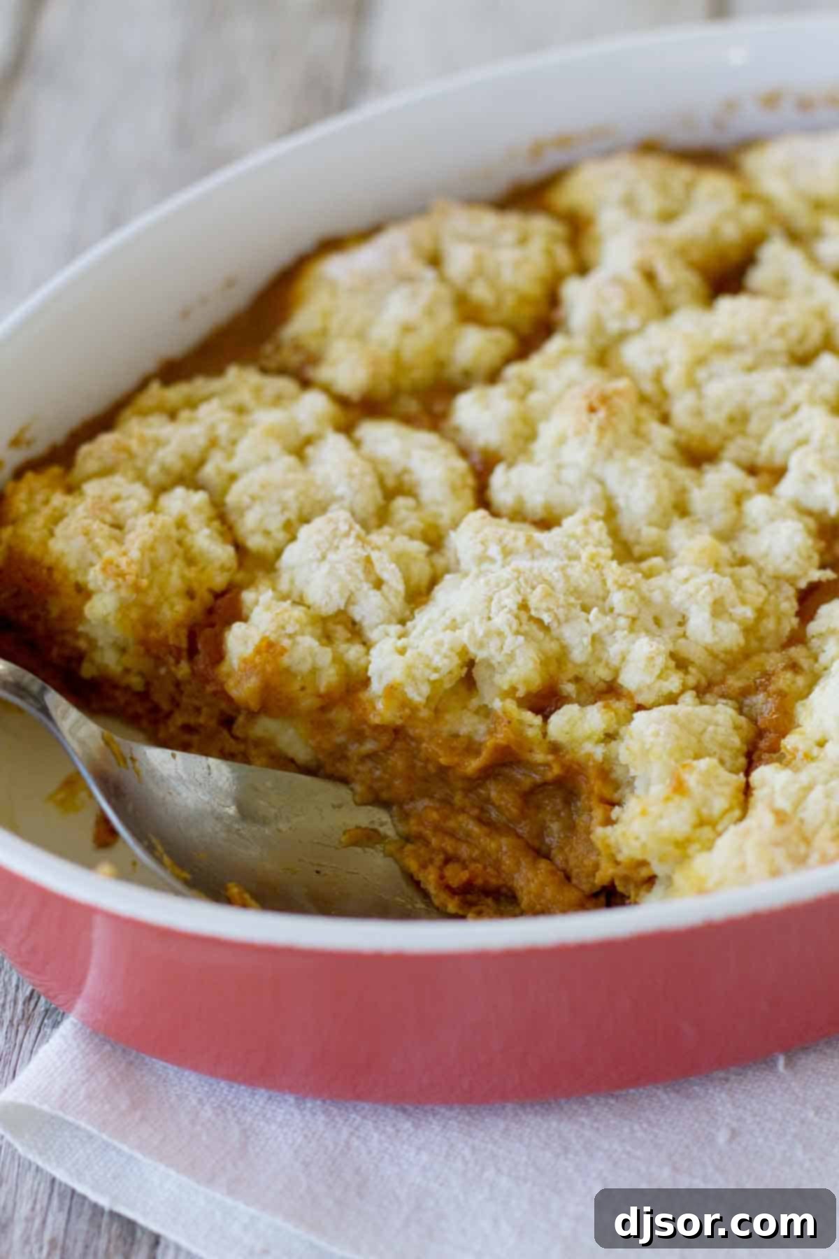 Dish filled with Pumpkin Cobbler - a fall dessert with pumpkin custard topped with a sweet biscuit topping.