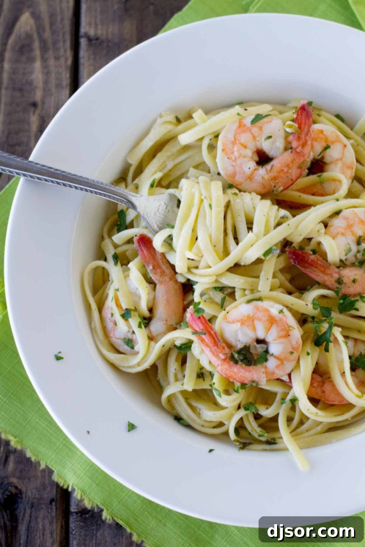 A restaurant worthy meal, this Lemon Pepper Shrimp Pasta is easy to prepare yet impressive and delicious! A close-up shot of linguine with perfectly cooked shrimp and a vibrant lemon pepper sauce.