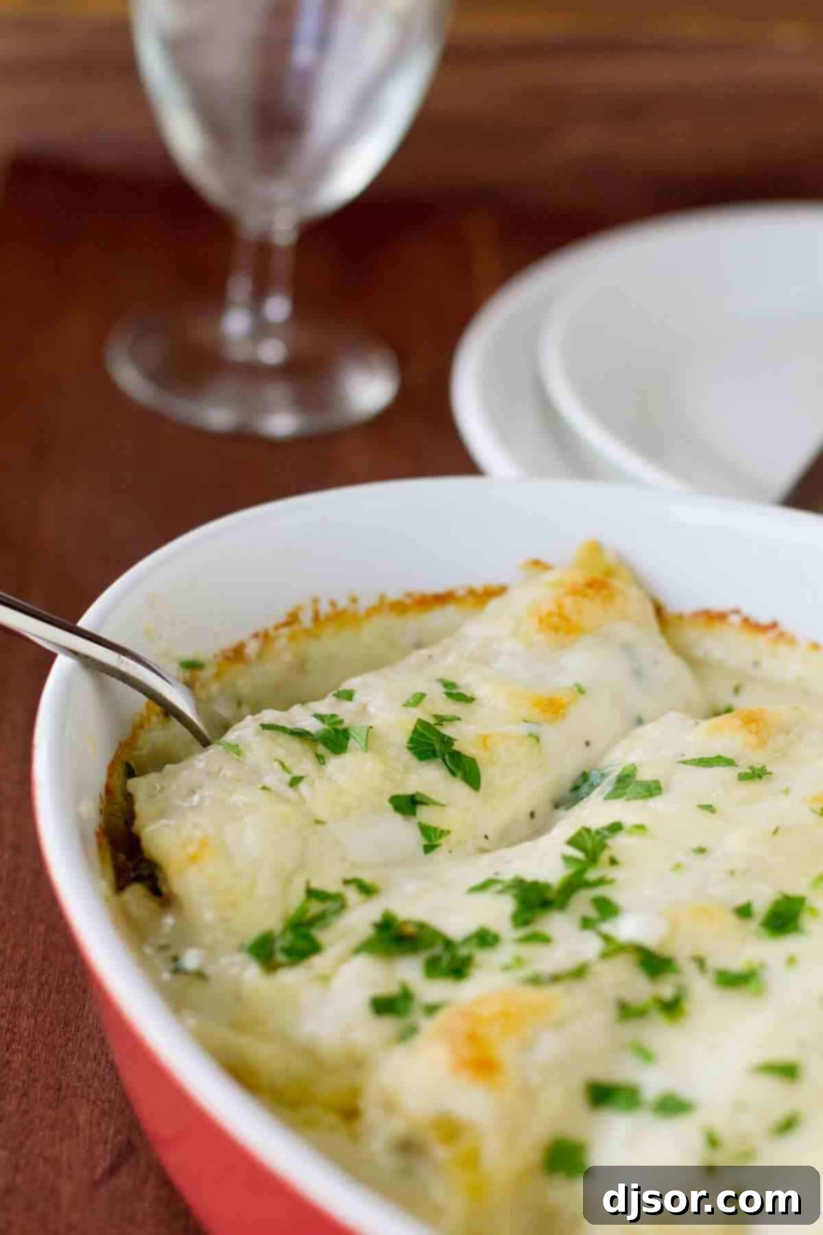 Creamy Chicken Manicotti with Mushrooms: A savory blend of chicken and mushrooms encased in pasta and smothered in white sauce. Baking dish with Chicken Manicotti with Mushrooms topped with fresh parsley, ready to serve.