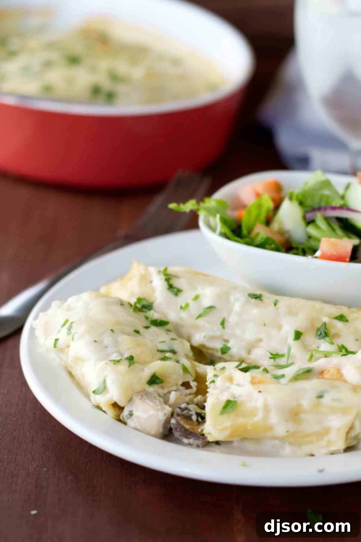 A close-up view of the delicious chicken and mushroom filling inside the manicotti. A serving of Chicken Manicotti with mushrooms cut in half, revealing the rich and creamy filling.