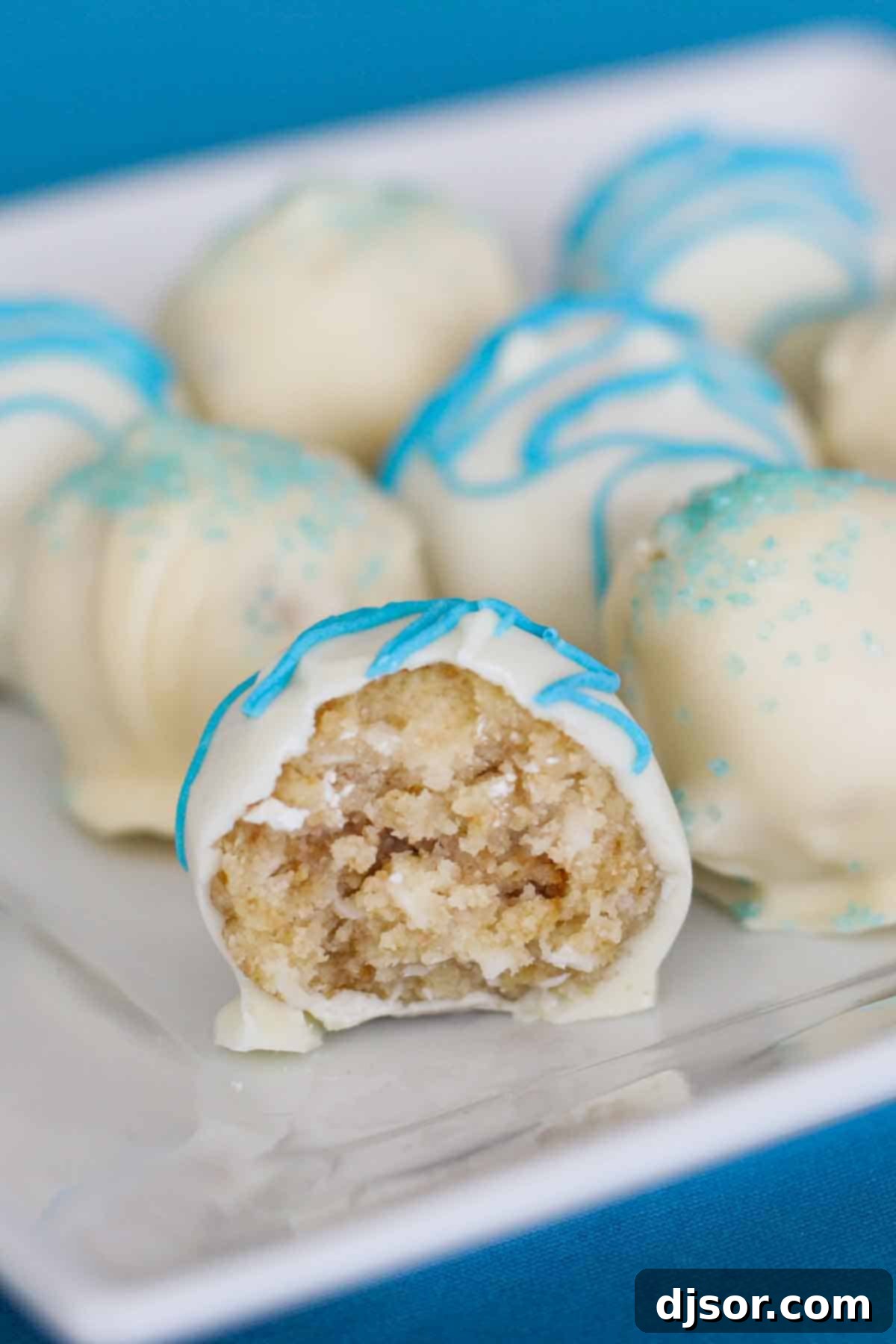 A single Coconut Cake Truffle with a bite taken from it, revealing the moist, coconut-infused interior.