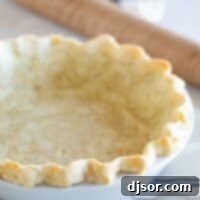 A perfectly baked golden-brown pie crust resting in a white ceramic pie dish, ready for filling.