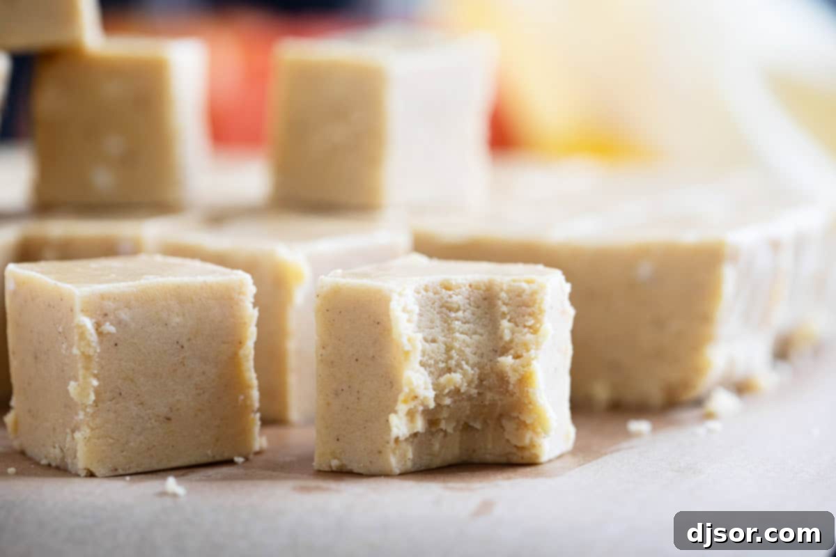 Squares of Pumpkin Fudge, with a bite taken from one piece, showcasing its creamy texture and festive appeal.