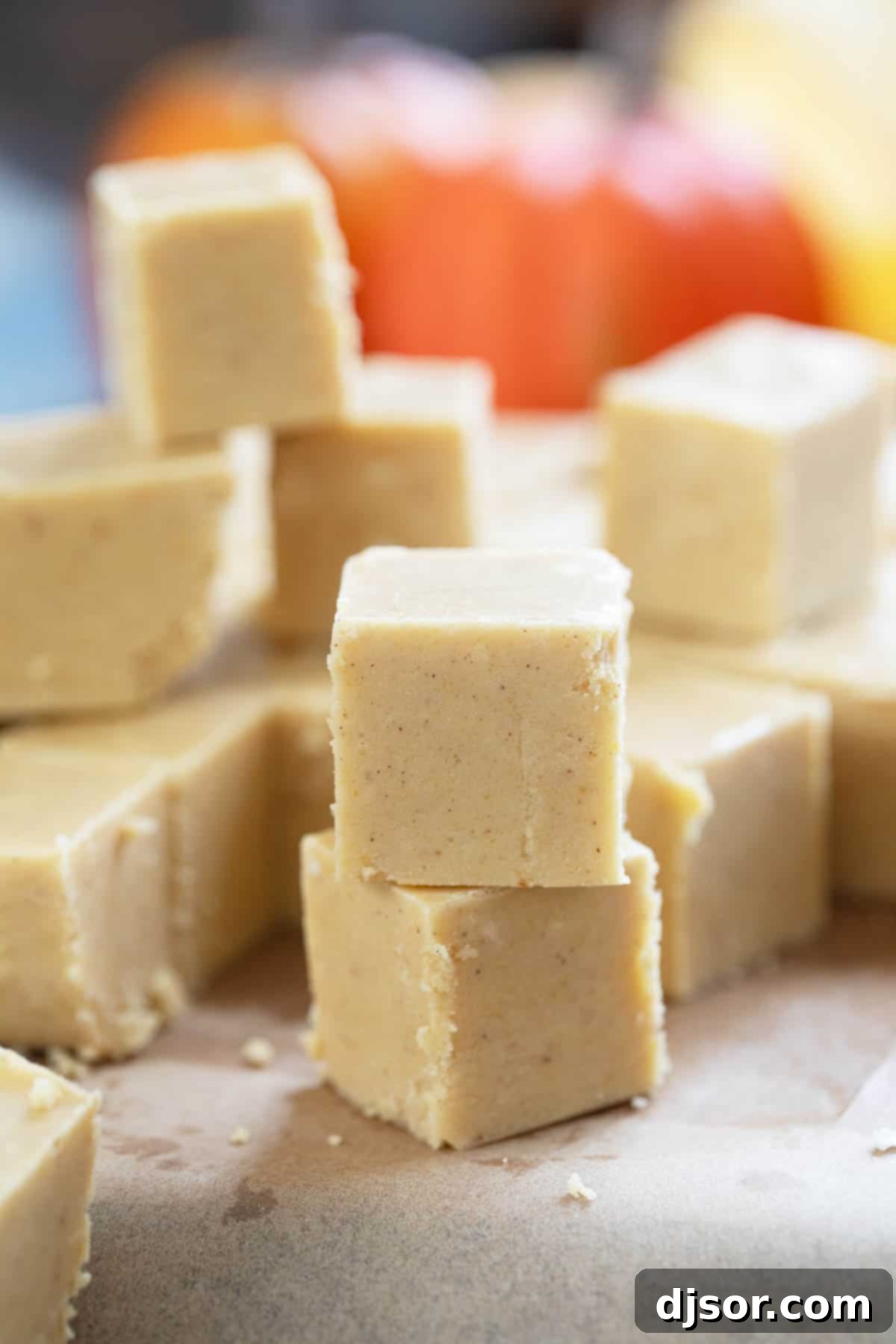 Perfectly cut squares of homemade pumpkin fudge, stacked and ready to enjoy on a rustic surface.