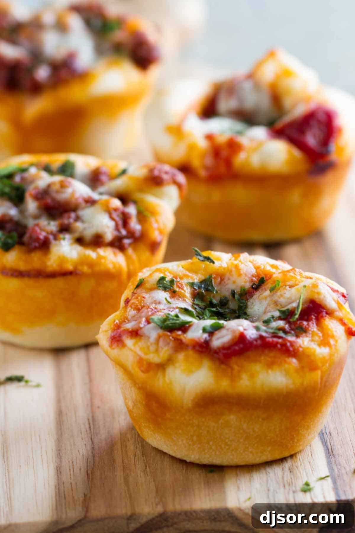 Savory Pizza Muffins 3 Freshly baked Pizza Cups arranged neatly on a wooden cutting board.