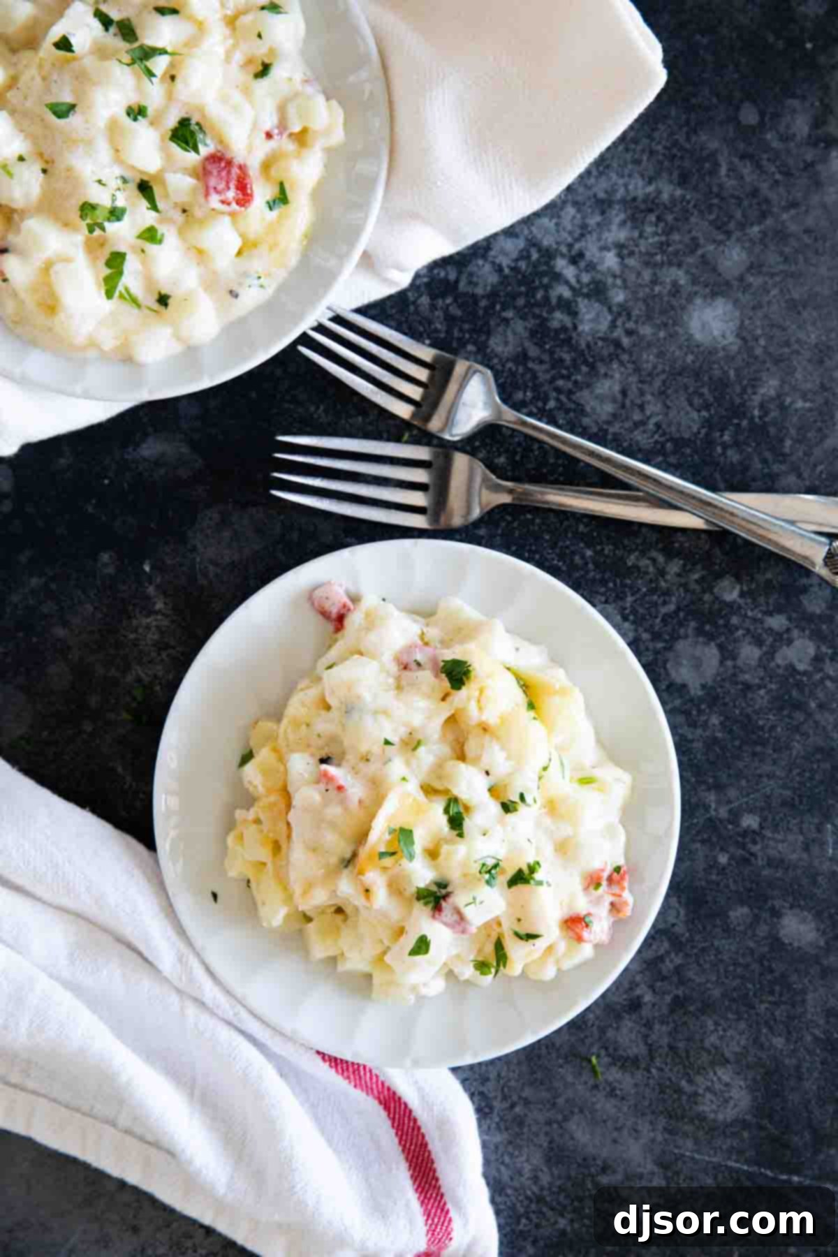 Individual plates with servings of Crockpot Cheesy Potatoes and forks, ready to be enjoyed.