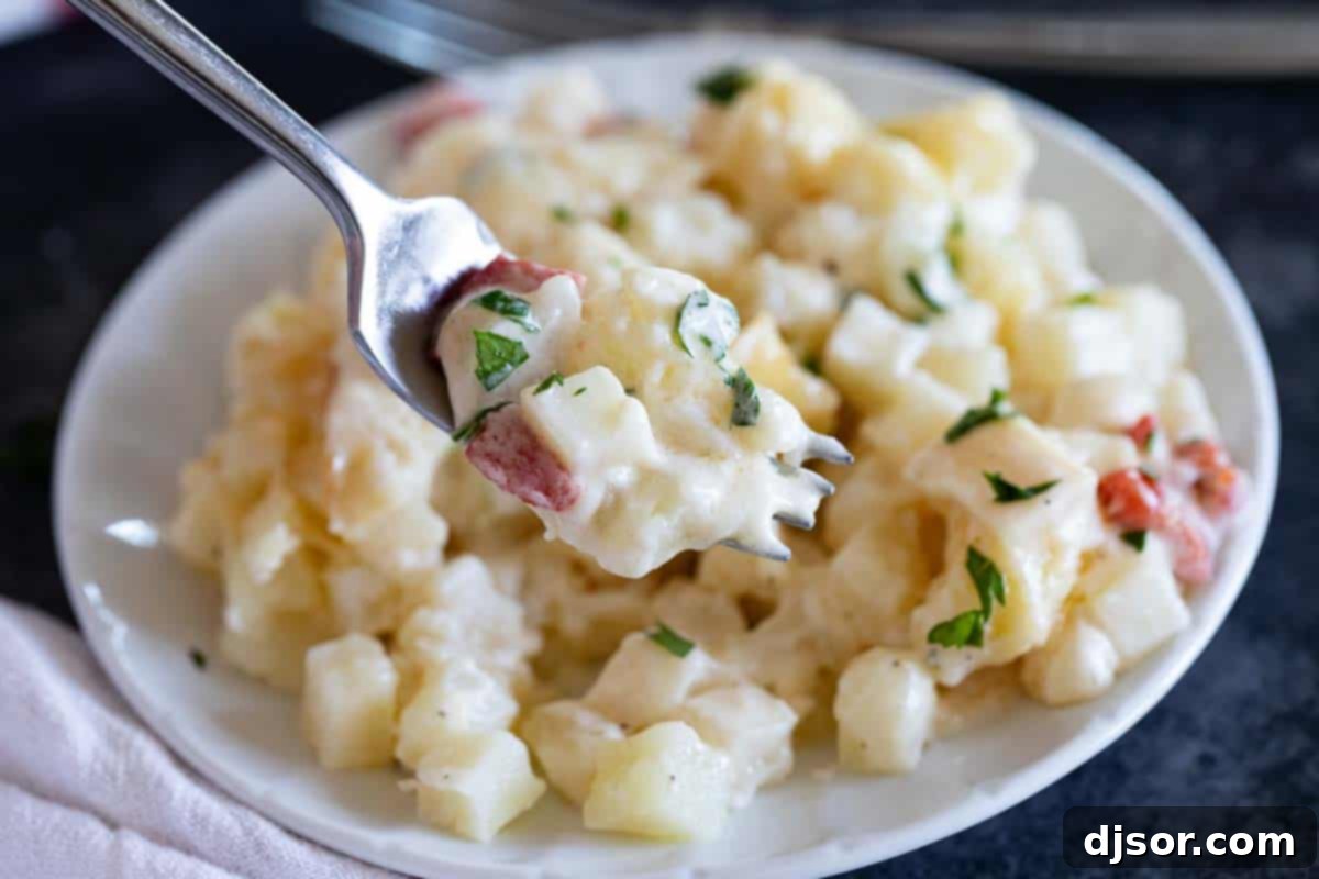 A person taking a delicious bite of Crockpot Cheesy Potatoes from a plate.