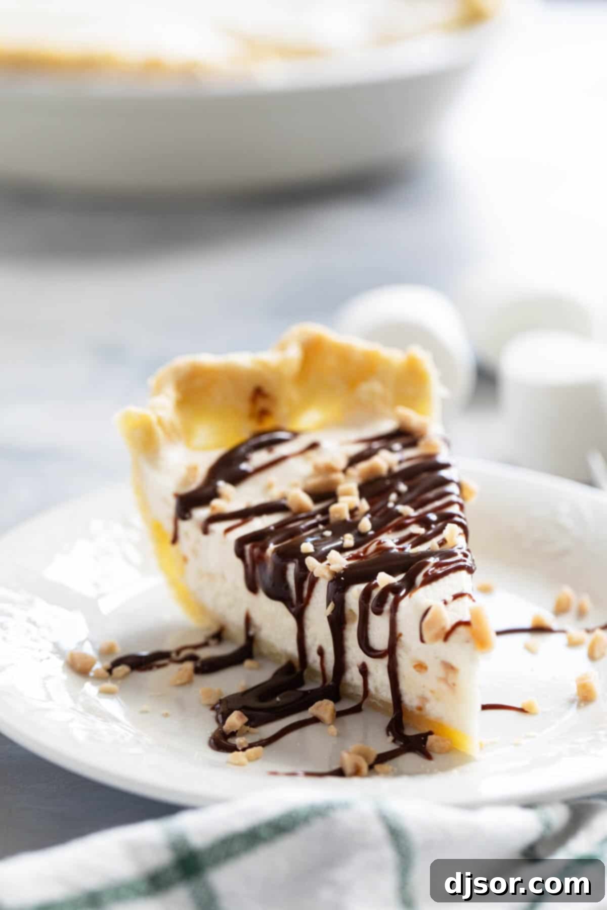 Slice of Toffee Marshmallow Pie with hot fudge drizzled over the top, and sprinkled with toffee pieces.