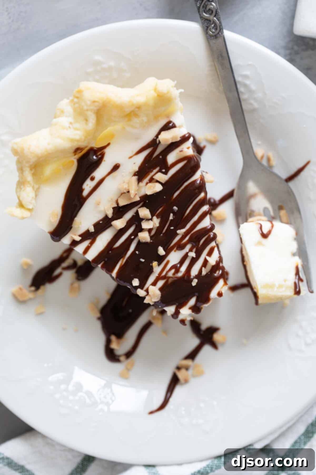 Slice of Toffee Marshmallow Pie topped with hot fudge and toffee pieces.