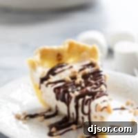 Slice of Toffee Marshmallow Pie with hot fudge drizzled over the top, and sprinkled with toffee pieces.