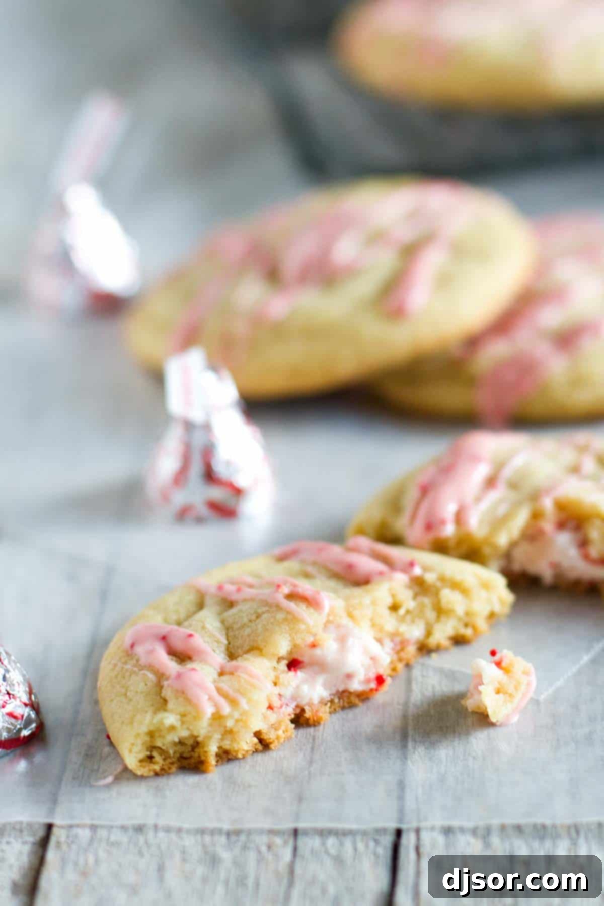 A Candy Cane Kiss stuffed pudding cookie broken in half to reveal the melted peppermint kiss inside.