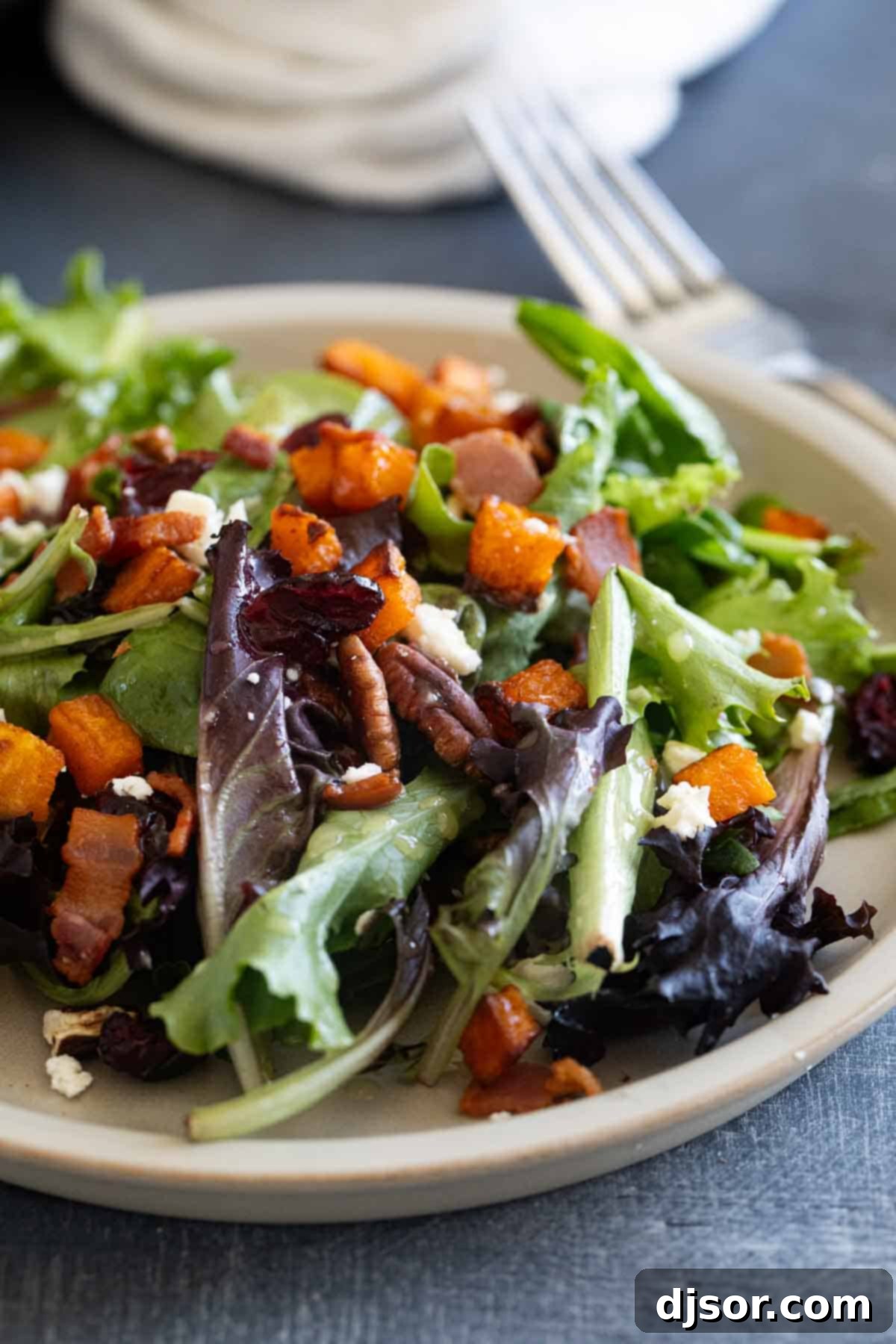 Autumn Harvest Medley 8 A single serving of Fall Harvest Salad presented on a white dinner plate, accompanied by a fork, ready to be enjoyed.